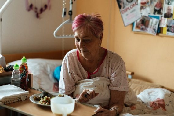Elderly woman enjoying a meal in a cozy retirement home setting.