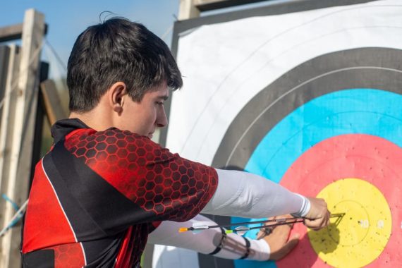 Focused young archer hitting the bullseye with precision outdoors.
